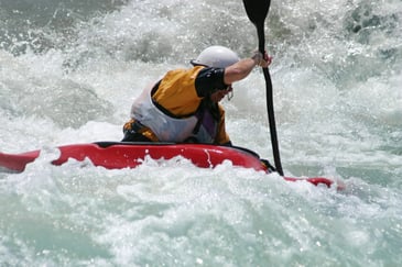 A man kayaking on rapids. 