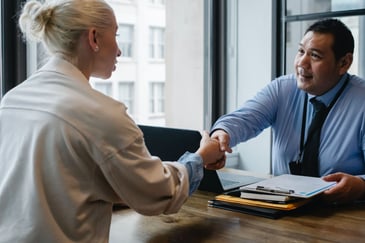 A businessman shaking hands with a new graduate, as he implements key strategies to hire graduates to improve the business’s talent pipeline.  