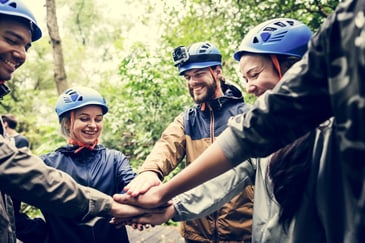 A group of people in a circle bonding through an outdoor team building event. 