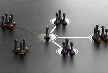 A central business owner pawn in the centre with five groups of pawns connecting to the central one which form a cohesive leadership team of a business that are aligned on their responsibilities and delegation of tasks. 