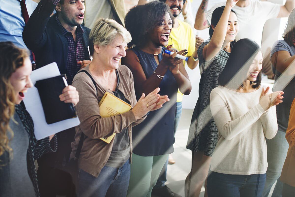 A group of people clapping to boost workplace optimism and productivity.