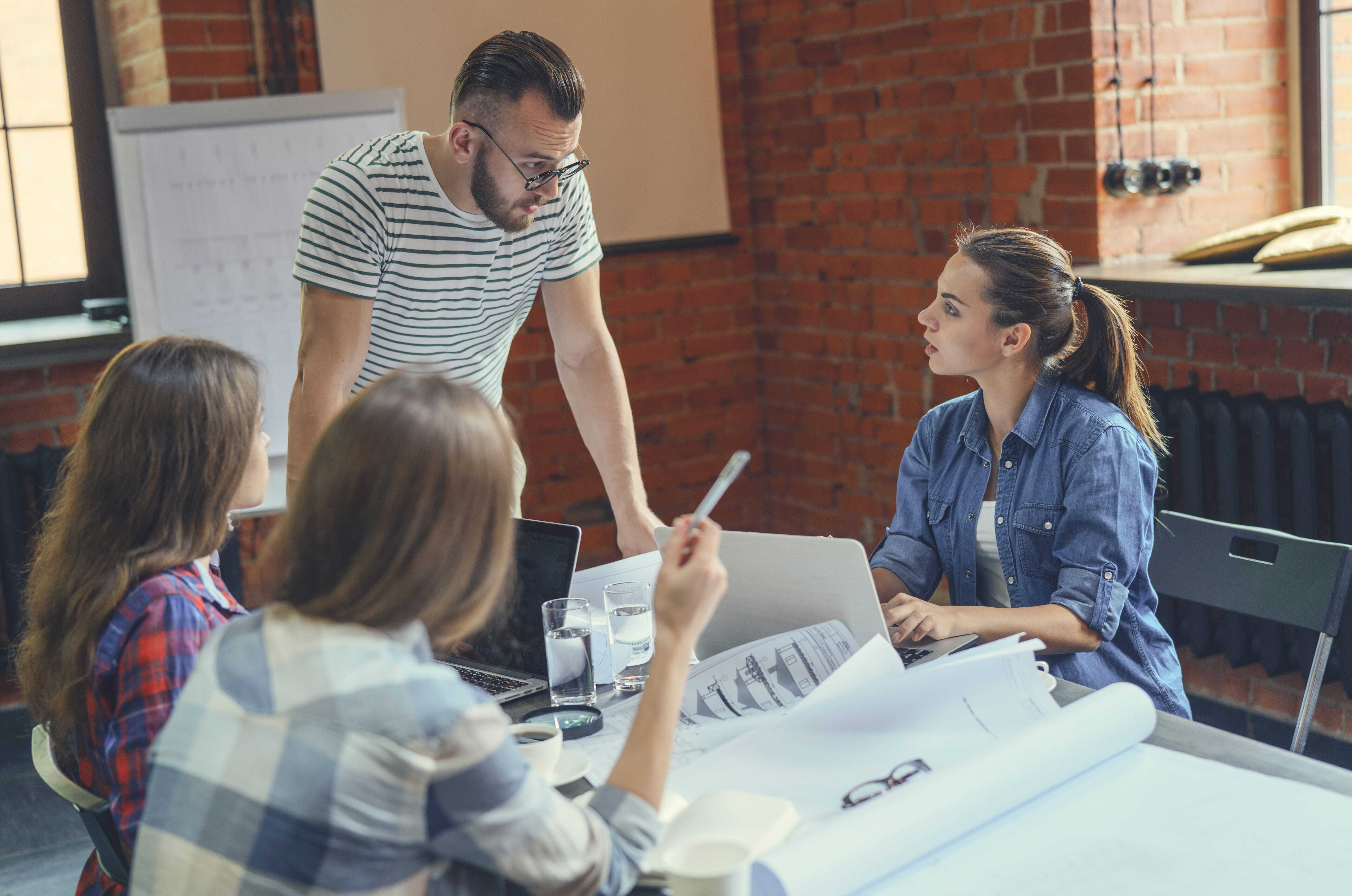 Manager discussing project plans with team members representing talent development vs talent management in everyday work.