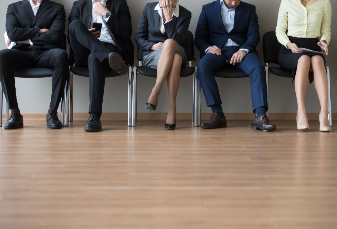 Five people sitting on chairs against a wall as they wait for a long time to see the business owner of a business who does not treat people like their greatest asset yet.