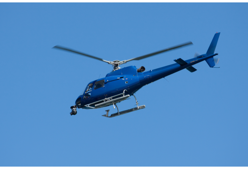 A dark blue helicopter flying through the clear blue sky, reflecting the role a leader takes when following the helicopter view. 