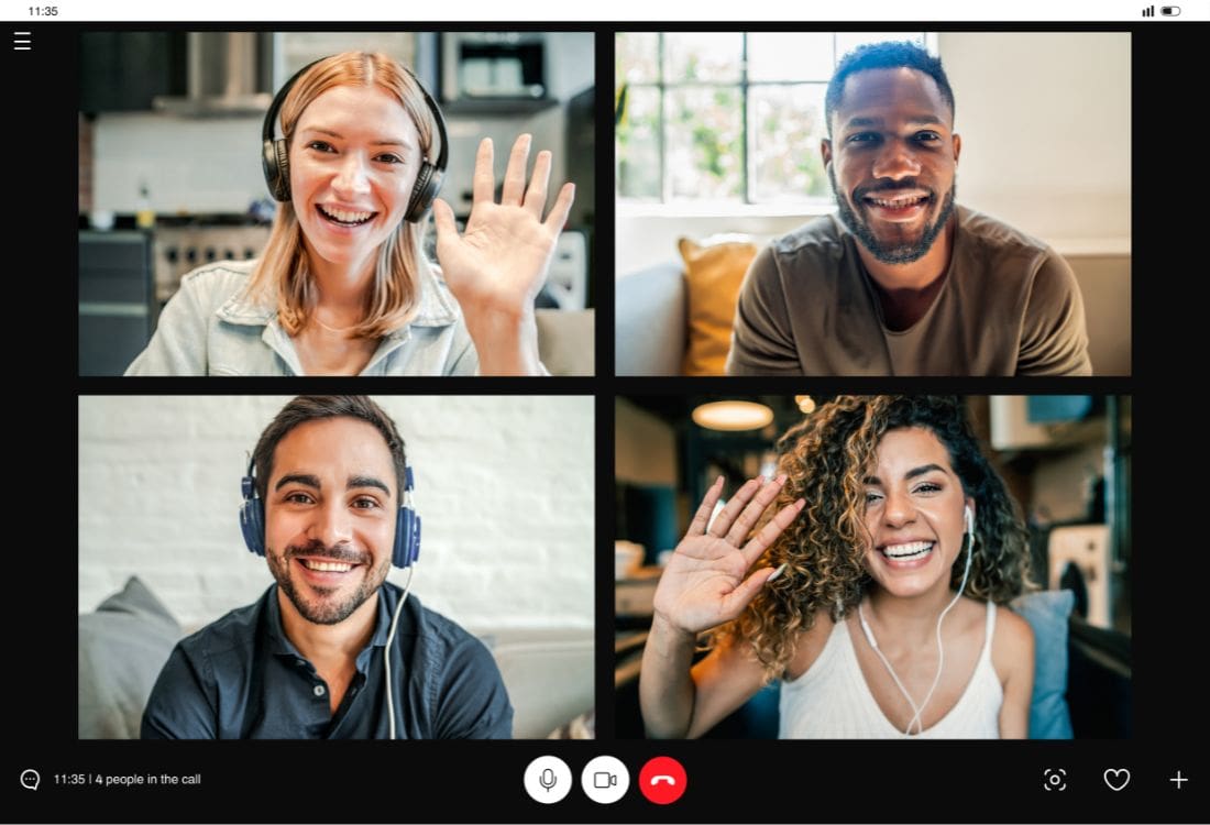 Four co-workers having a virtual meeting effectively while smiling and waving at each other through their cameras.