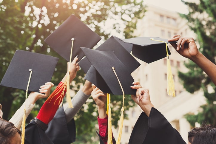 A group of graduates waving their graduation caps in the air as they celebrate starting a new graduate training programme