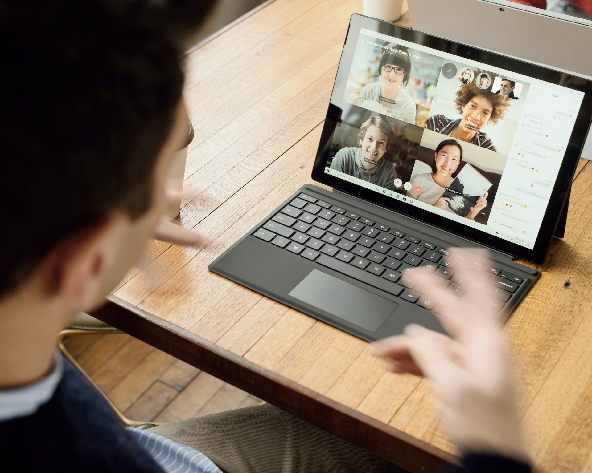 A man having a virtual meeting on his laptop with four colleagues while working from home.