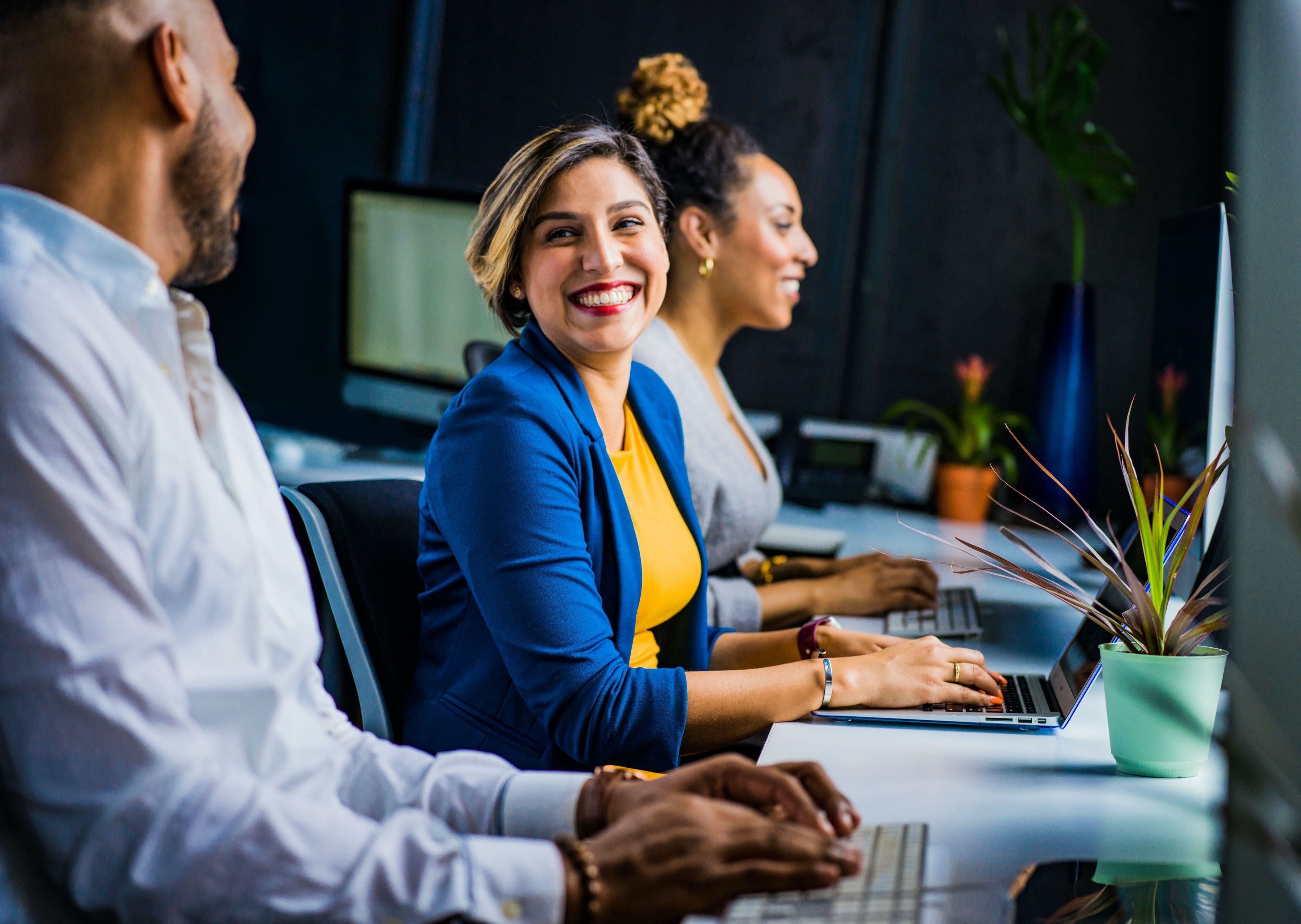 Three team members at their desks laughing with each other as they incorporate their company culture into their work life